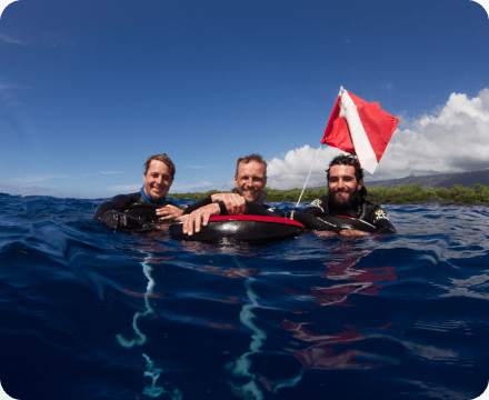 three smiling divers on the water